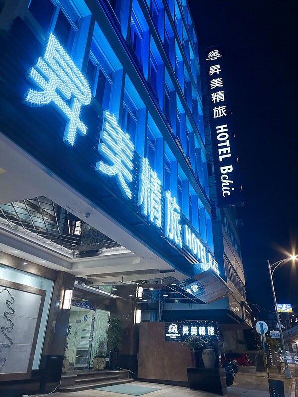 A hotel with illuminated signage in a foreign language, a modern facade, and a welcoming entrance area.