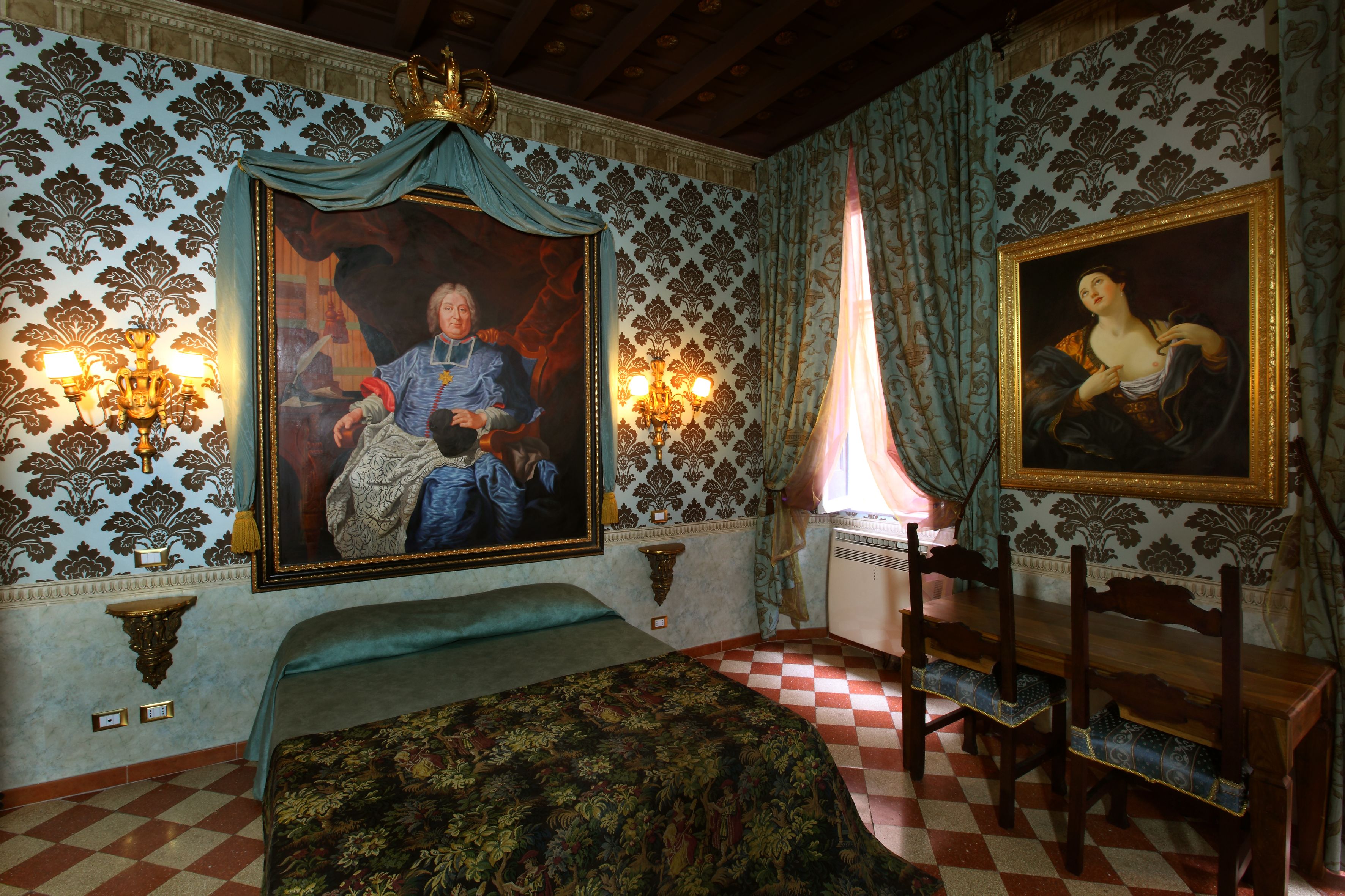 A room with ornate wallpaper, a large bed with a floral bedspread, two wall-mounted lamps, and a checkered floor.