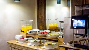 A breakfast buffet with various fruits and juices, a television, and a wooden counter. - The Abergavenny Hotel  (Abergavenny)