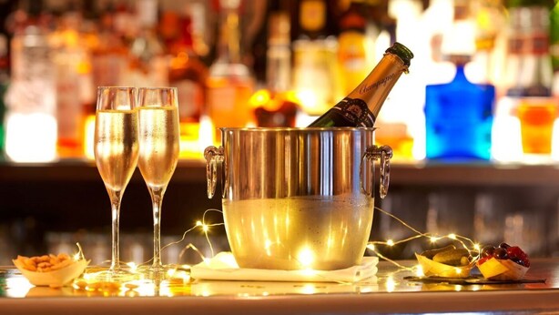 A bar setting with two glasses of champagne, a bottle in a metal bucket, and a bowl of fruit on a table. - The Abergavenny Hotel  (Abergavenny)