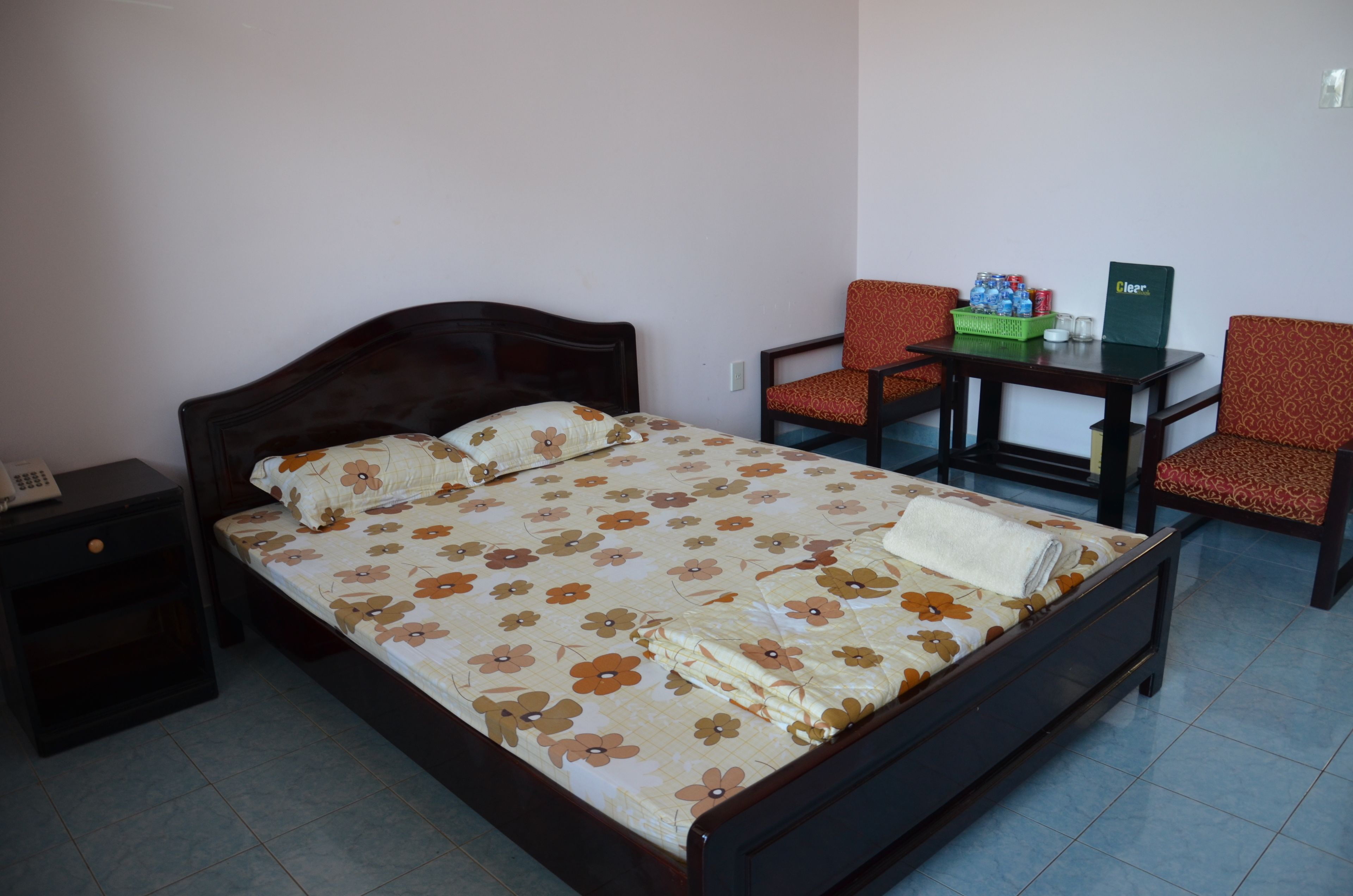 A bedroom with a bed, two chairs, a small table, and a nightstand.