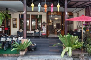 A hotel entrance with a staircase, potted plants, and bicycles.