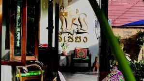 A room with wooden furniture, hanging lanterns, and a wall with a decorative animal carving. - Lee Chiang Hotel (Chiang Mai)
