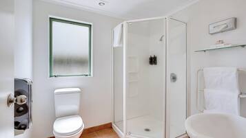 Een badkamer met toilet, douchecabine en bad.