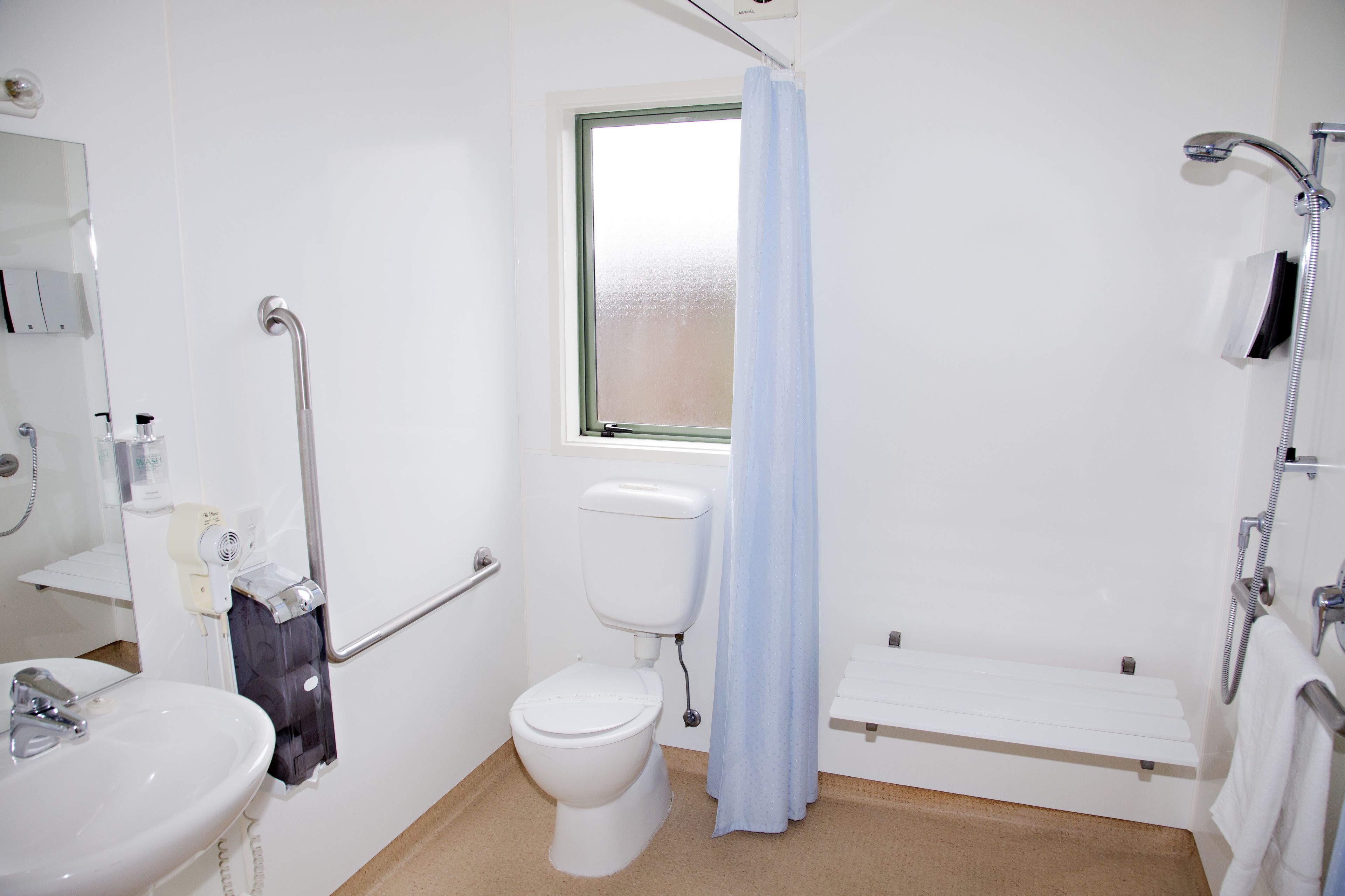 A bathroom with a white sink, toilet, and shower area.