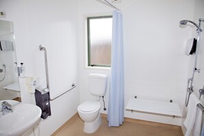 Un baño con lavamanos, inodoro y zona de ducha blanca.
