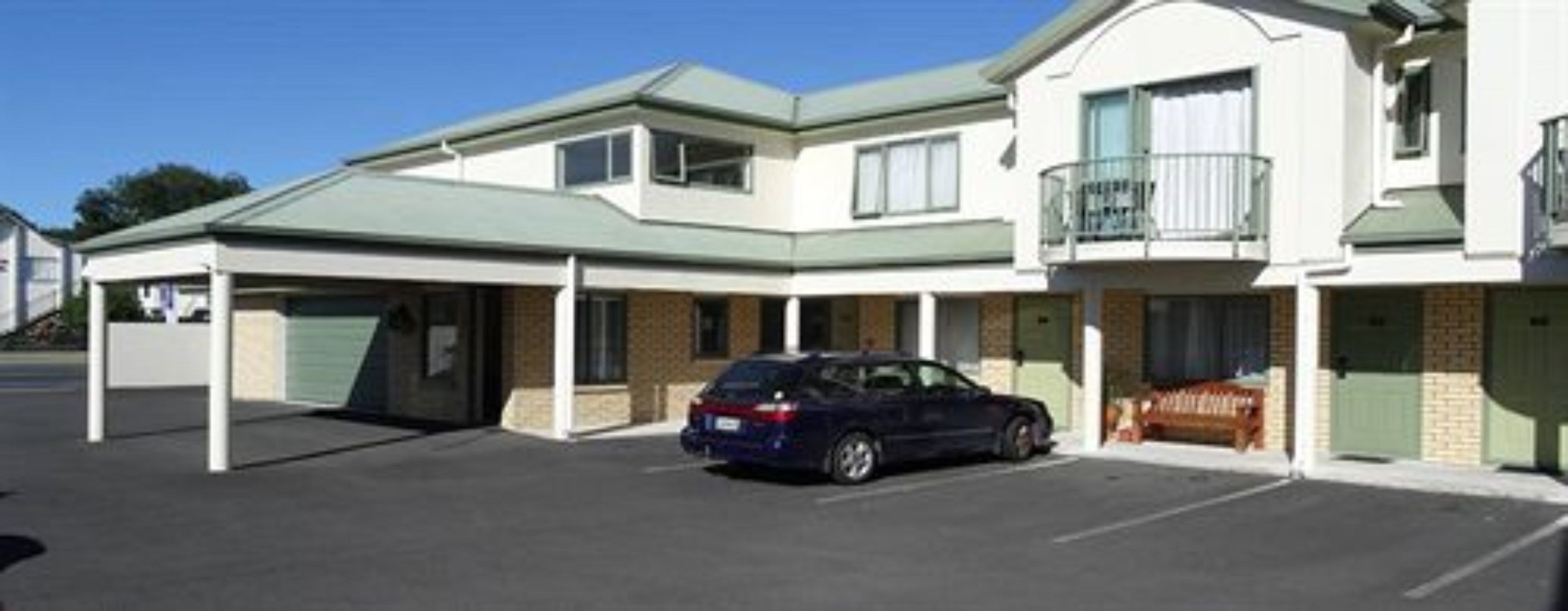A two-story motel with a covered parking area and a car parked inside.