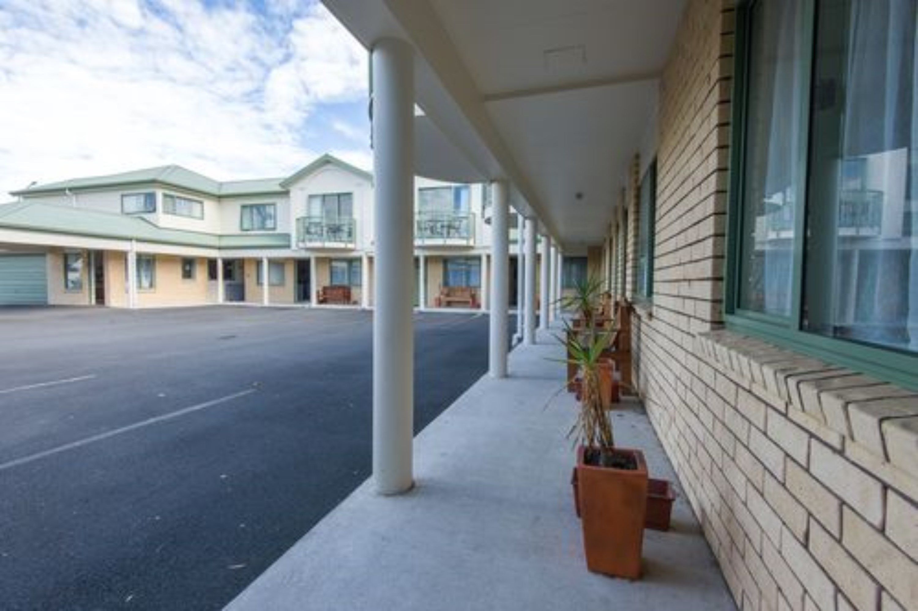 A hotel with a covered walkway, multiple balconies, and a parking lot.