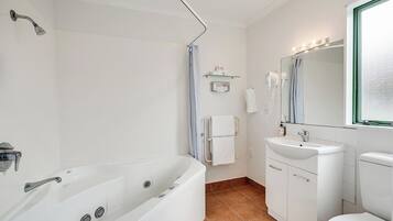 A modern bathroom with a bathtub, a sink, a toilet, and a shower.