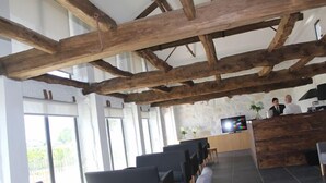 A reception area with a wooden ceiling, a reception desk, and a TV screen. - Lousada Country Hotel (Lousada)