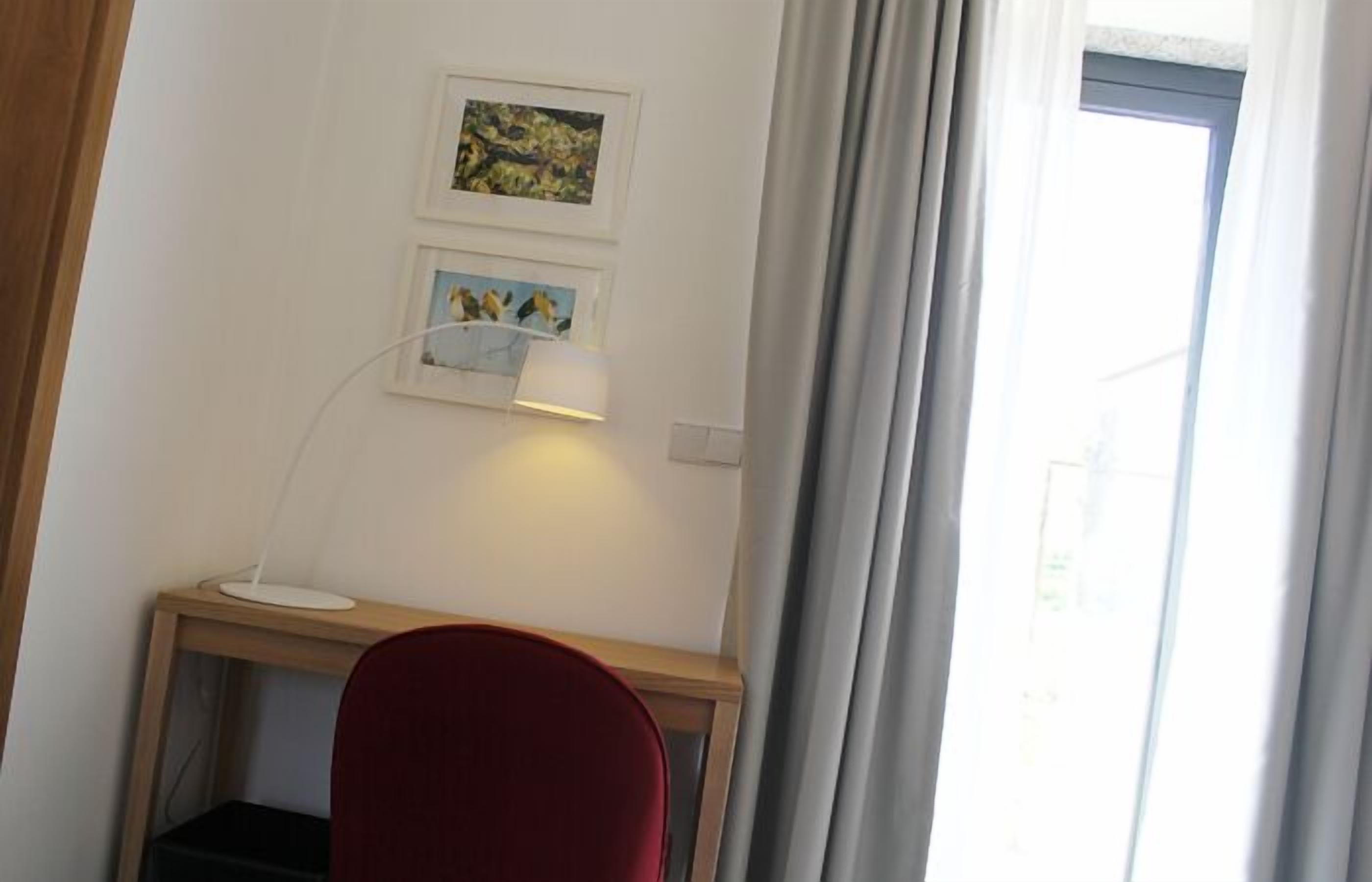 A room with a desk, a red chair, and two framed pictures on the wall.