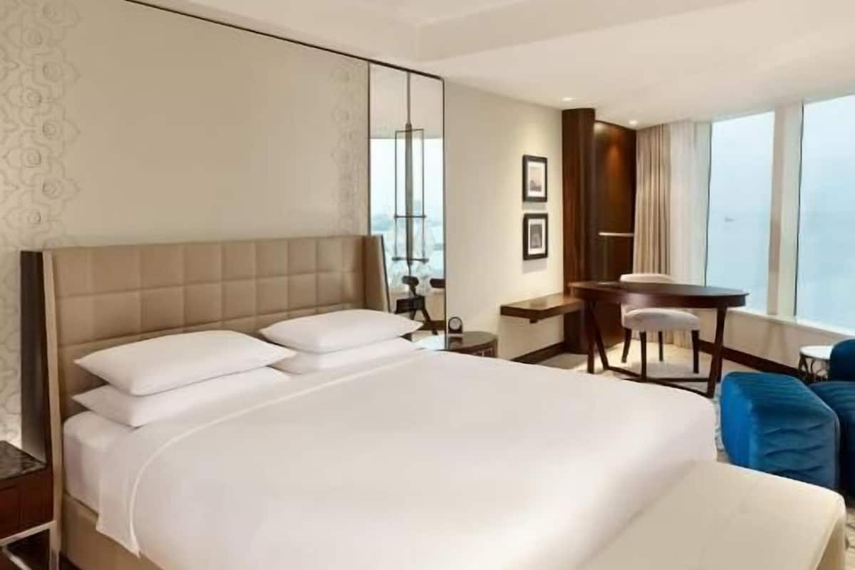 Una habitació d'hotel amb un llit gran, una taula de treball, una cadira i vista a la ciutat.