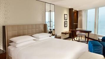 Habitación de hotel con una cama grande, un escritorio, una silla y vistas a la ciudad.