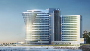 Un hôtel moderne doté d’une façade en verre incurvée, situé près d’une plage.