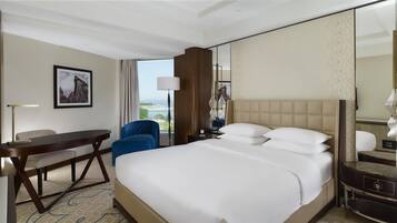 A hotel room with a bed, a desk, a chair, a lamp, and a large window with a view.