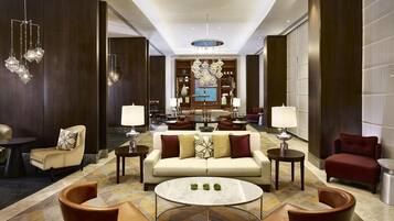 A spacious lobby with a central seating area, a chandelier, and a view of the dining area.
