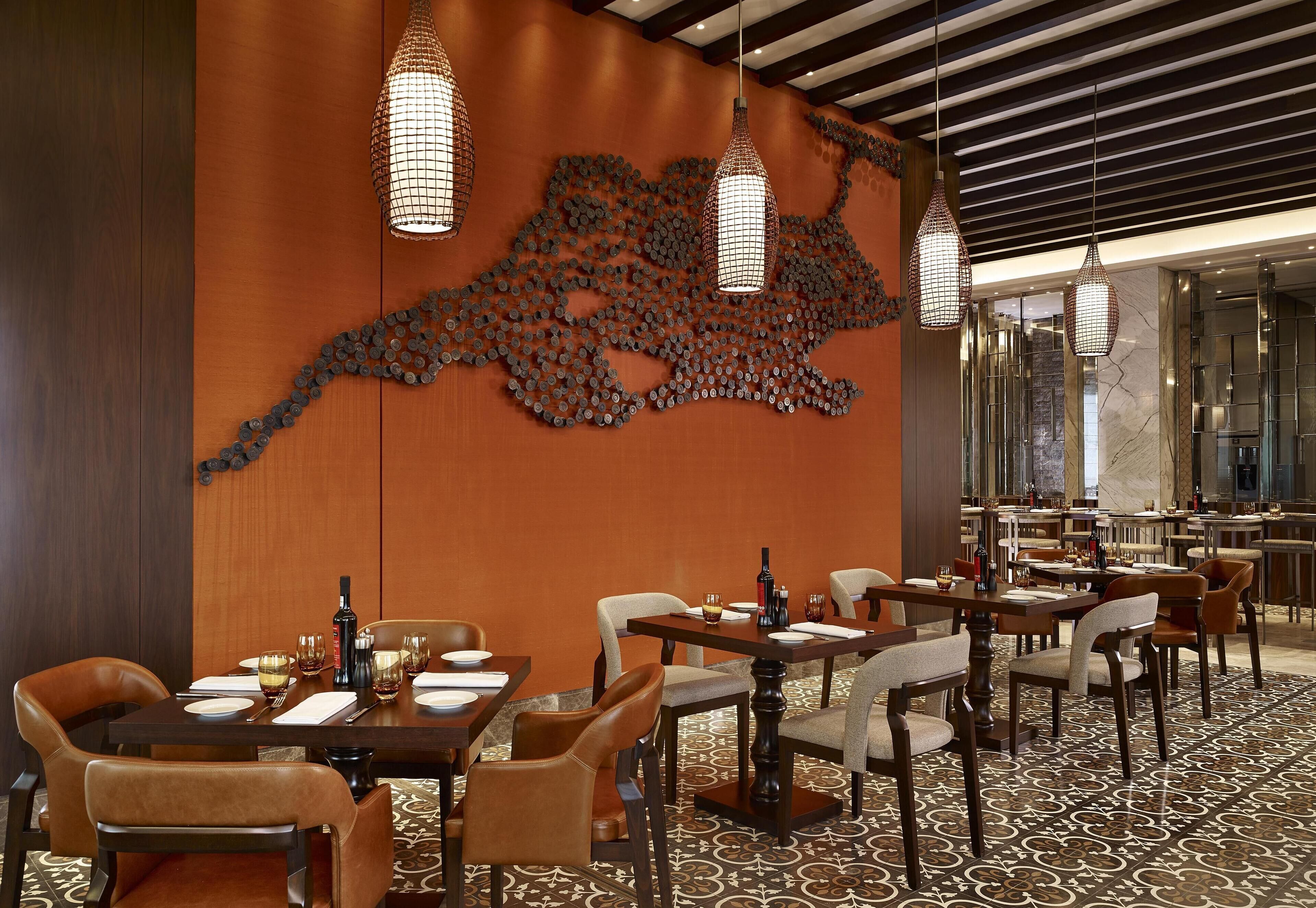 A restaurant with tables set for dining, a decorative wall art piece, and hanging pendant lights.