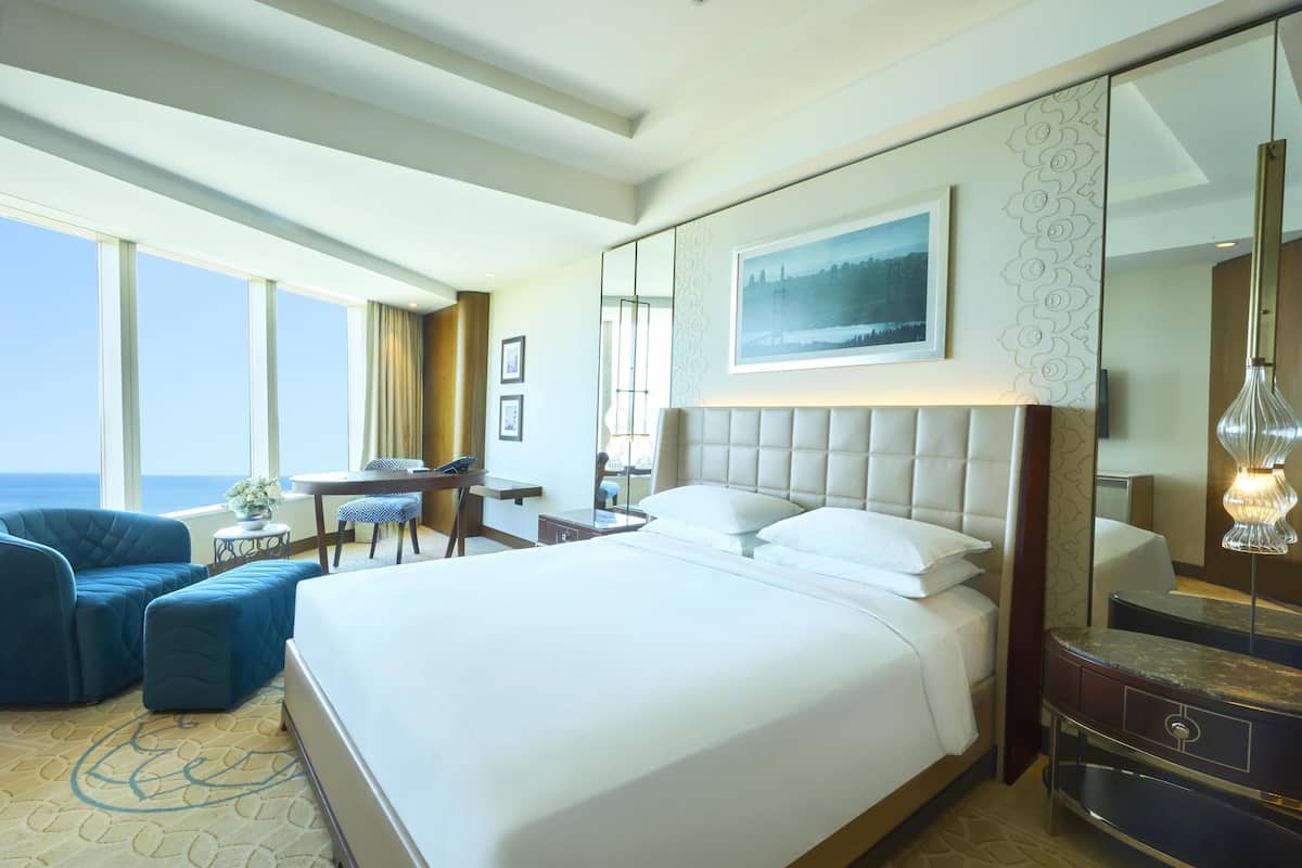 Habitació d'hotel amb un llit gran, una taula de treball, una cadira i vista a l'oceà.
