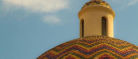 Un bâtiment surmonté d’un dôme aux tuiles colorées et d’une croix.