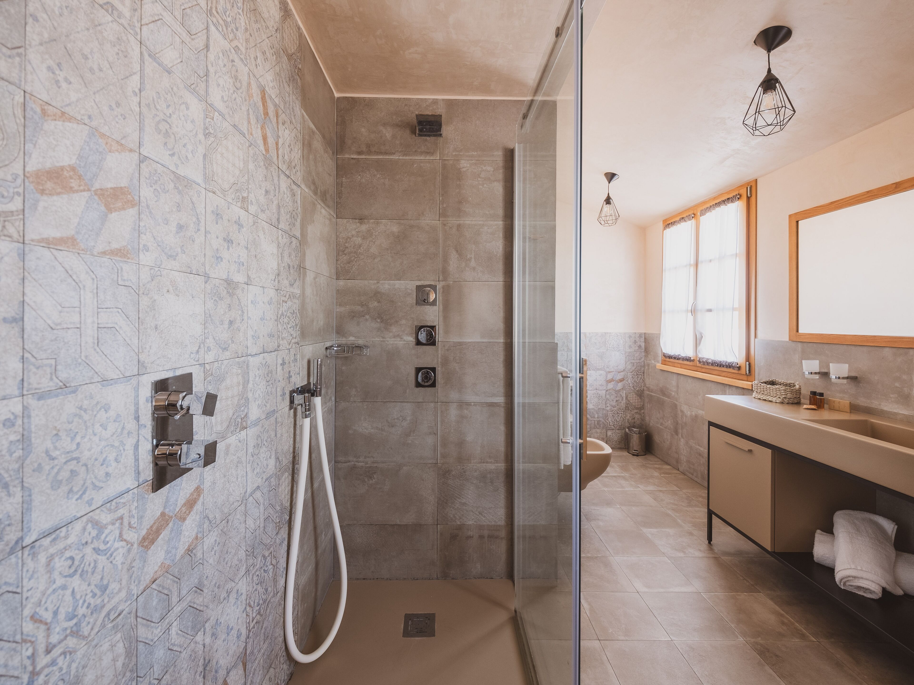 A modern bathroom with a glass-enclosed shower, a vanity with a sink, and a mirror above the counter.