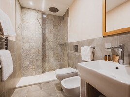 Un bagno moderno dotato di doccia, WC e lavandino.