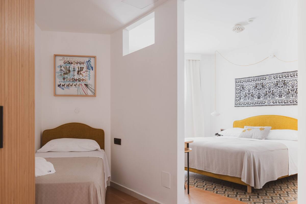A hotel room with two beds, a wooden headboard, a patterned rug, and artwork on the walls.