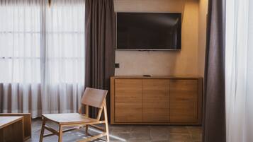 Una sala moderna con un aparador de madera, un televisor de pantalla plana montado en la pared y una silla de madera.
