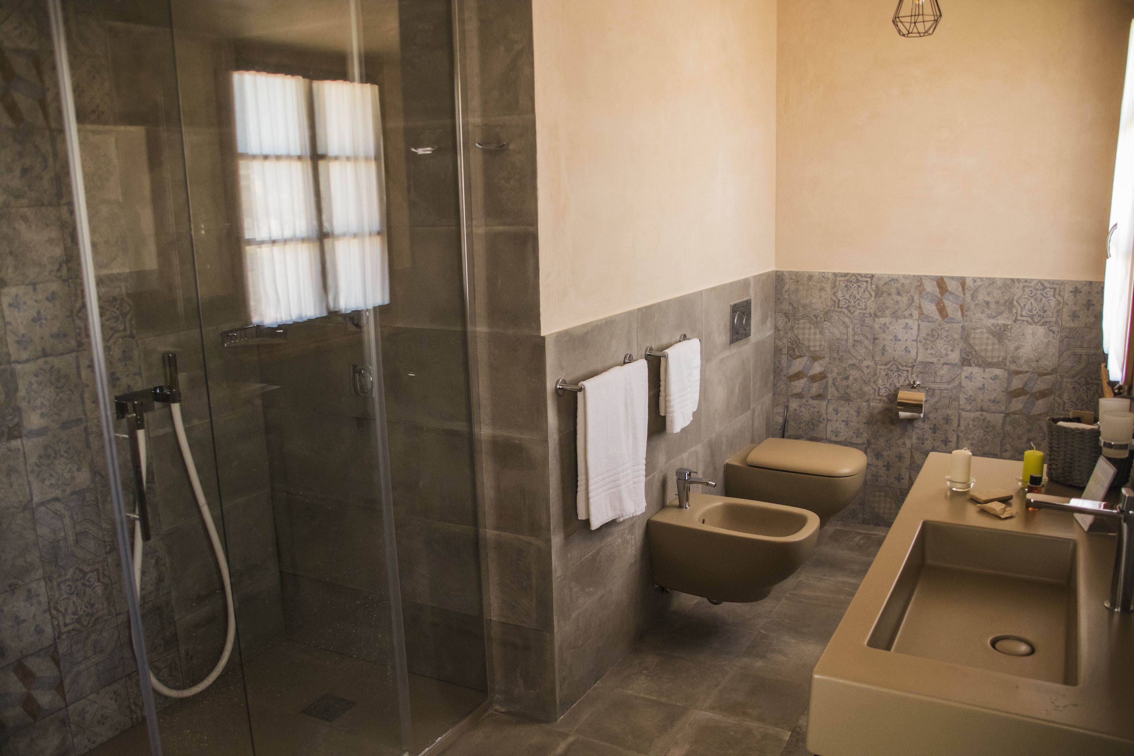 A modern bathroom with a glass-enclosed shower, a beige sink, and a bidet.