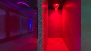 Een gang met een douchecel met rood licht en een doorgang met blauw licht.