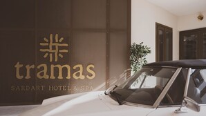 En vit bil parkerad framför en byggnad med en skylt där det står "tramas SARDART HOTEL & SPA".