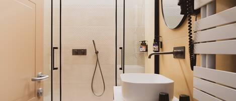 A modern bathroom with a glass-enclosed shower, a white sink, and a towel rack.