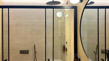 A modern bathroom with a glass shower enclosure, a round mirror, and a wall-mounted towel rack.