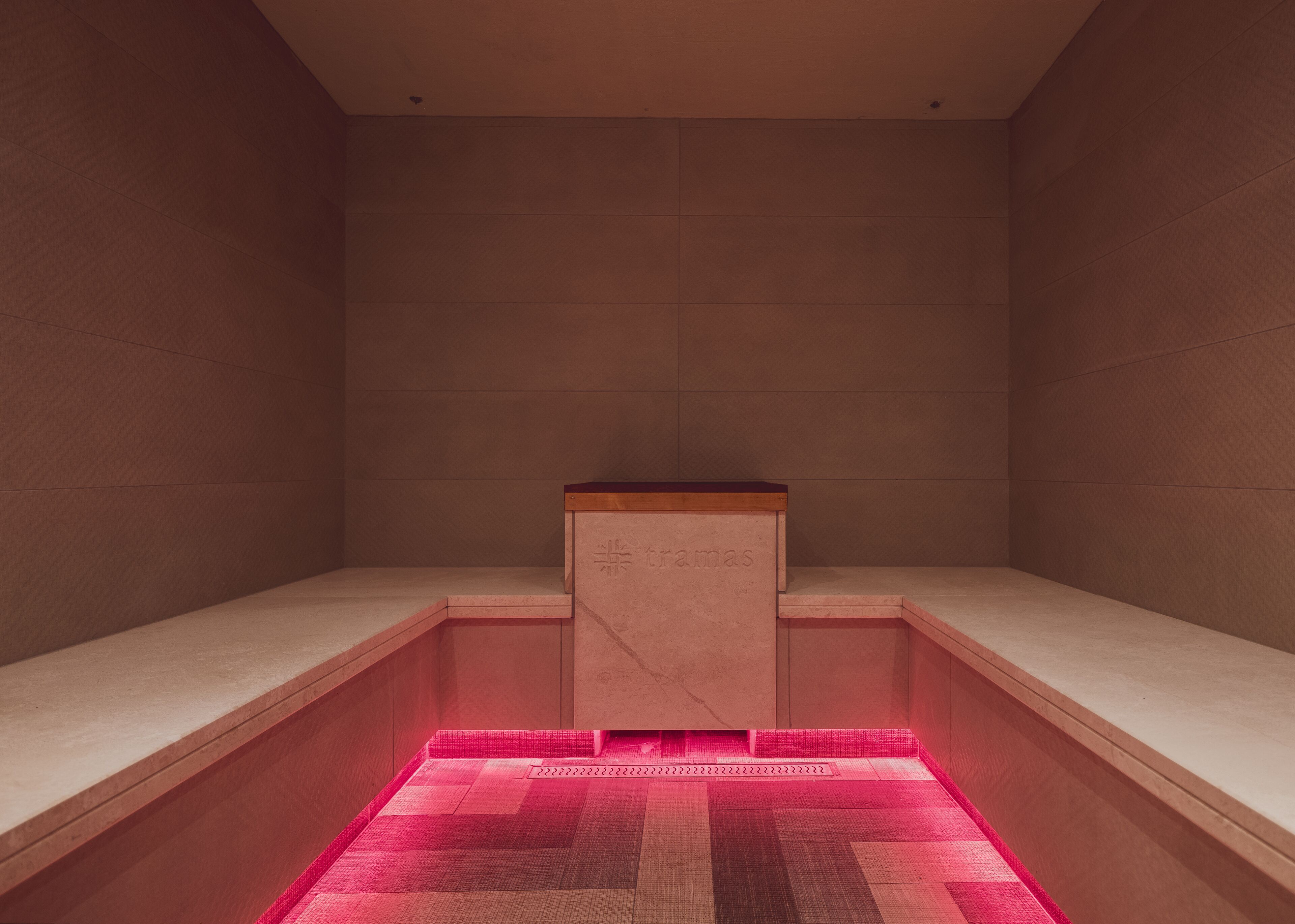 Una habitación minimalista con un banco de madera, una pequeña mesa y un suelo con diseño.