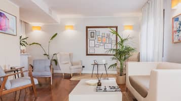 Uma sala de estar moderna com sofá, poltronas, mesa de centro e parede decorada com quadros.