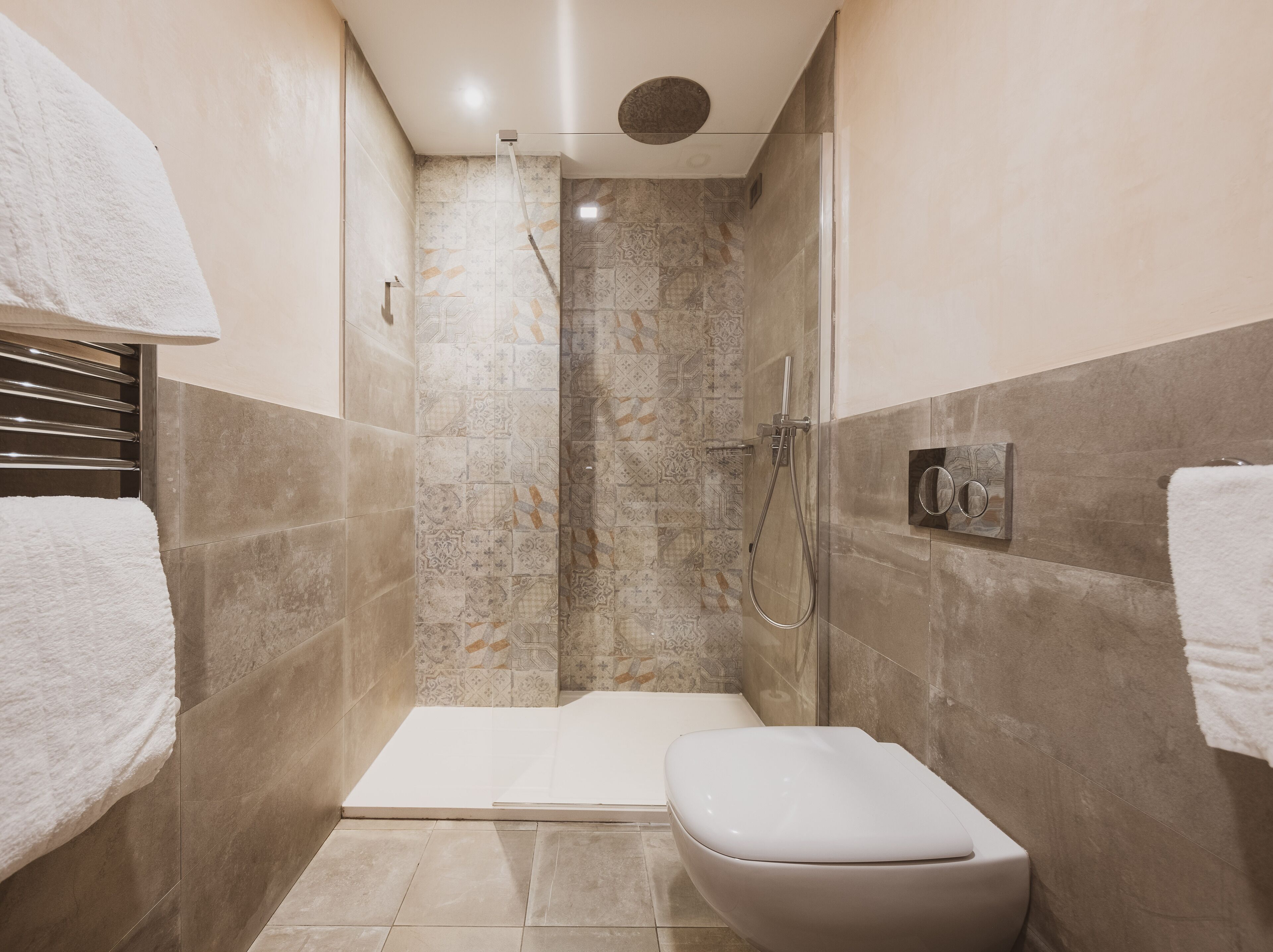 A modern bathroom with a glass-enclosed shower, a white toilet, and a towel rack.