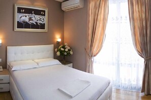 Habitación de hotel con una cama grande, una mesita de noche, un jarrón con flores y un cuadro en la pared.