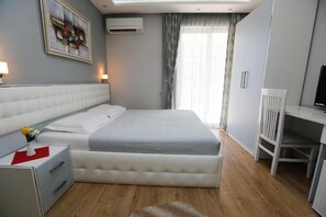 A modern bedroom with a large bed, bedside tables, a desk, and a television.
