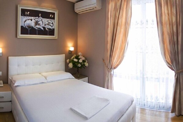 Une chambre d’hôtel avec un grand lit, une table de chevet, un vase de fleurs et un tableau au mur.