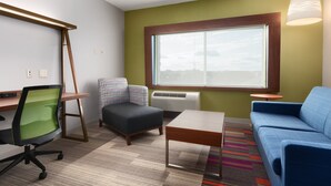 Una habitación moderna con escritorio, silla de oficina, sofá y una pequeña mesa.