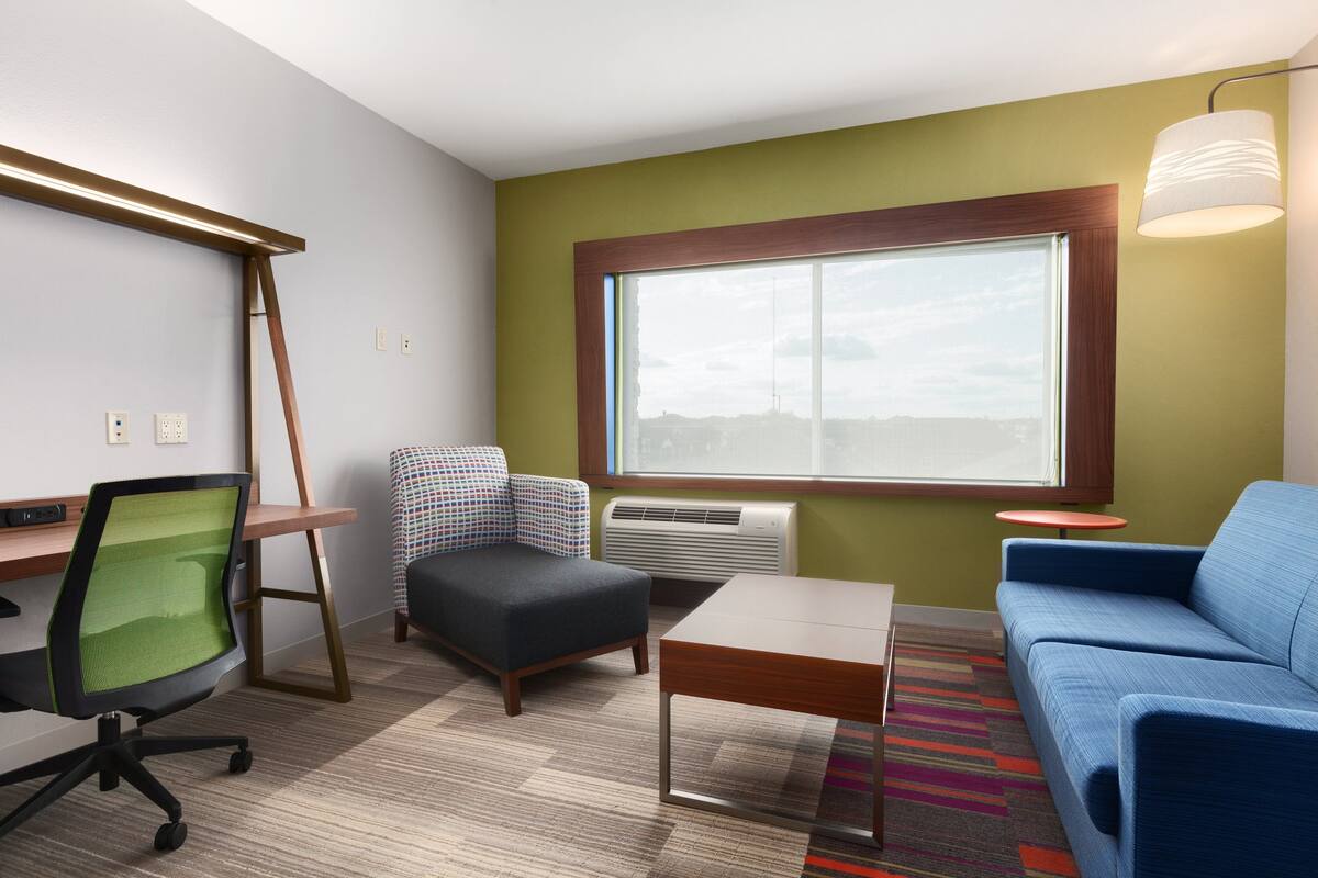 A modern room with a desk, office chair, sofa, and a small table.