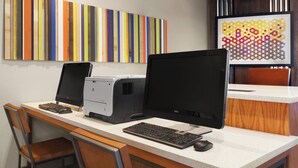 A workspace with two monitors, a keyboard, and a printer on a desk.