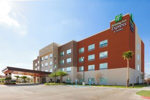 Een Holiday Inn Express & Suites hotel met een modern design, bestaande uit een plat dak, meerdere ramen en een heldere lucht.