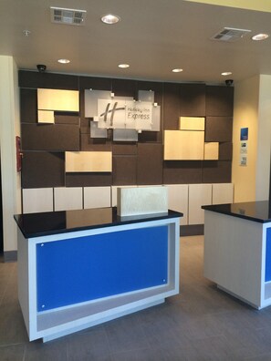 A reception desk with a Holiday Inn Express sign, a blue counter, and a wall with a geometric pattern. - Holiday Inn Express & Suites Tahlequah by IHG (Tahlequah)