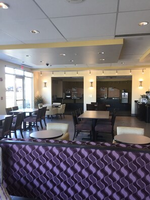 A restaurant with multiple dining tables and chairs, a kitchen area, and a seating area with patterned cushions. - Holiday Inn Express & Suites Tahlequah by IHG (Tahlequah)