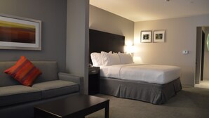 A hotel room with a bed, a sofa, a coffee table, and a nightstand. - Holiday Inn Express & Suites Tahlequah by IHG (Tahlequah)