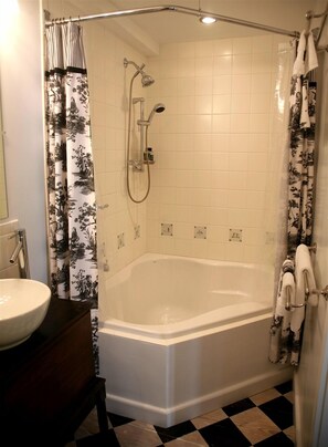 A bathroom with a bathtub, shower, and a sink. - The Stone House B&B (Hurley)