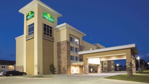 Un hotel La Quinta Inn & Suites de diseño moderno, con una entrada destacada y un área de estacionamiento techada.