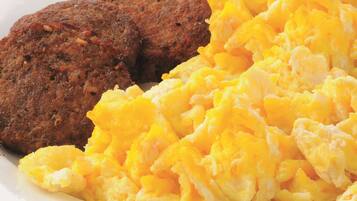 Scrambled eggs and two meat patties on a plate.