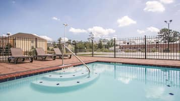 Una piscina al aire libre, sillones reclinables de piscina