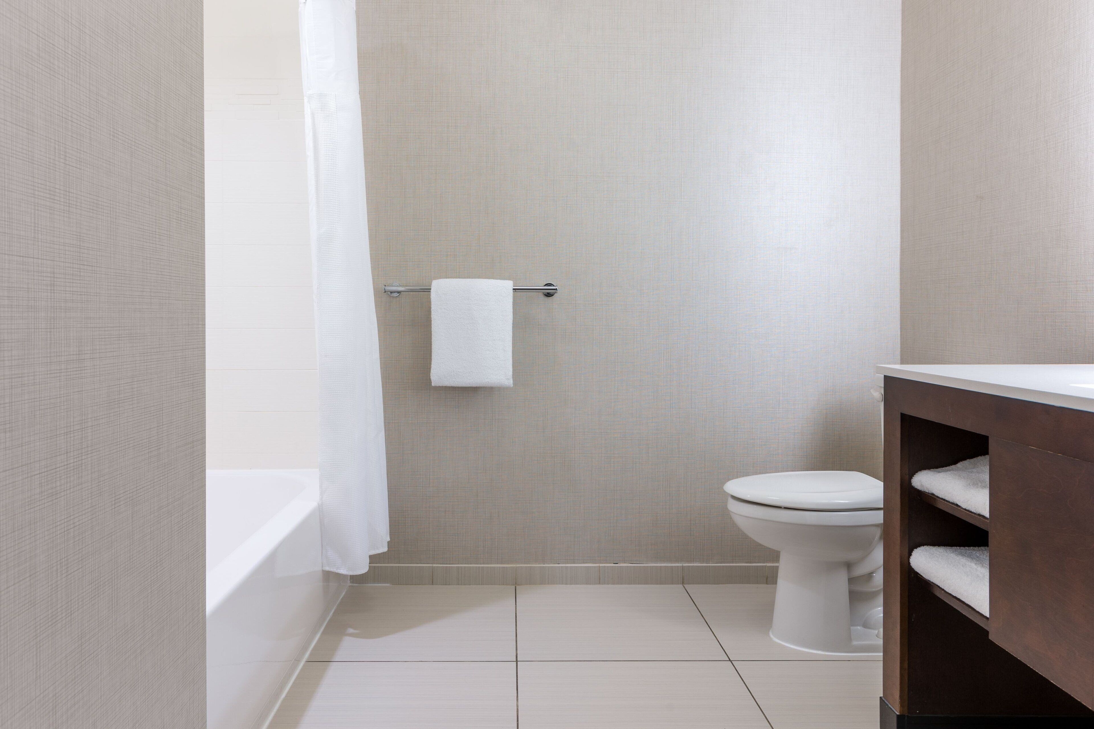 A bathroom with a bathtub, toilet, and a towel rack.